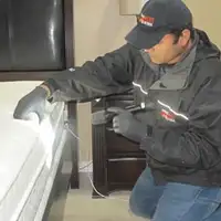 Bed bug inspection technician checking a mattress and bed frame for signs of infestation in Portland, OR