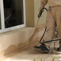 General pest control technician spraying exterior perimeter around a home in Portland, OR