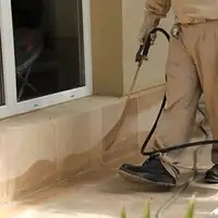 General pest control technician spraying exterior perimeter around a home in Portland, OR
