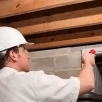 Termite inspection technician checking a basement wall and framing for termite activity in Portland, OR